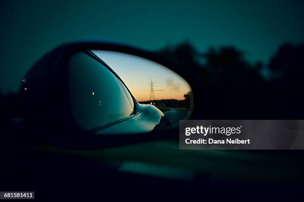 the sun setting in the rear view car mirror. - car mirror stock-fotos und bilder