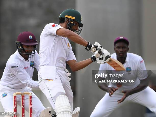 Shan Masood of Pakistan plays a cover shot as Jason Holder and wicketkeeper Shai Hope of the West Indies look on during the first day of play, of the...