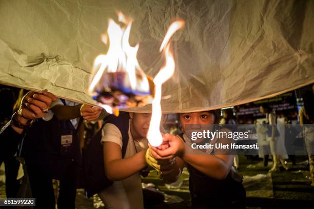 Buddhist follower girl light a lantern as they prepare release lanterns into the air on Borobudur temple during celebrations for Vesak Day on May 10,...