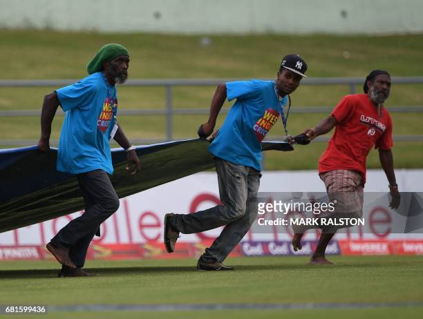 Ground staff run to place a cover over the wicket as rain delays play on the first day of the 3rd and final test match between Pakistan and the West...