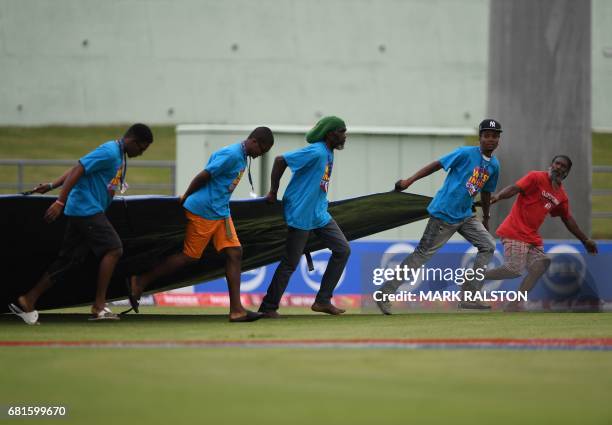 Ground staff run to place a cover over the wicket as rain delays play on the first day of the 3rd and final test match between Pakistan and the West...