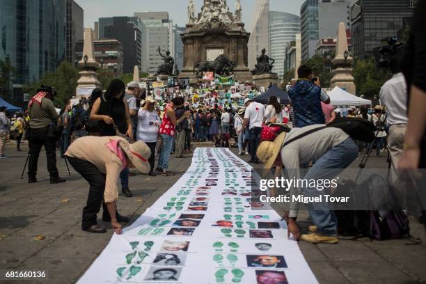 Protesters line up a banner with images of missing people, during a march on Mother's Day on May 10, 2017 in Mexico City, Mexico. Mothers whose...
