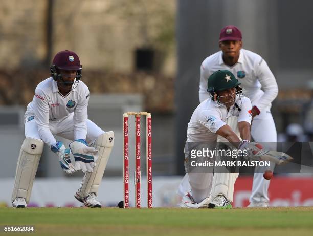 Batsman Younis Khan of Pakistan who is playing in his final test match, plays a sweep shot watched by West Indies wicketkeeper Shai Hope , during the...