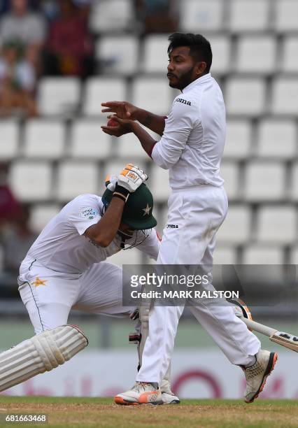 West Indies bowler Devendra Bishoo takes the ball as Babar Azam of Pakistan ducks during the first day of play, of the 3rd and final test match at...