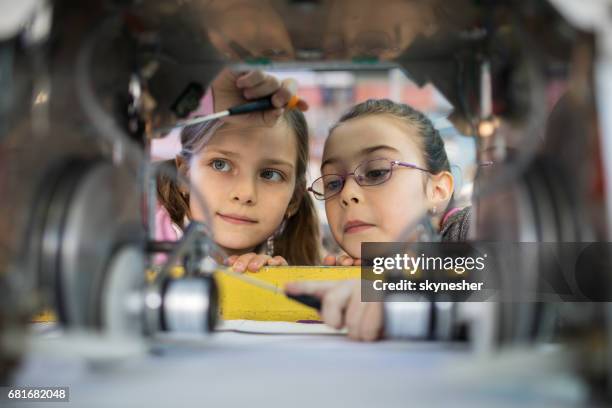 dos ingenieros poco trabajando en equipo, reparar un robot. - robótica fotografías e imágenes de stock