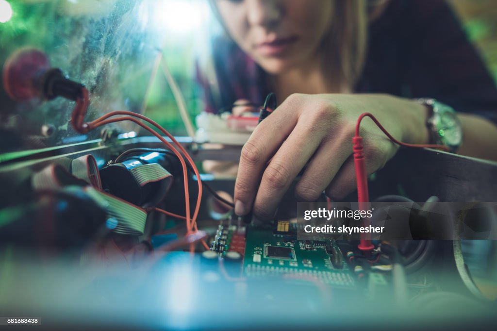 Close up of a woman repairing electrical component of a computer.