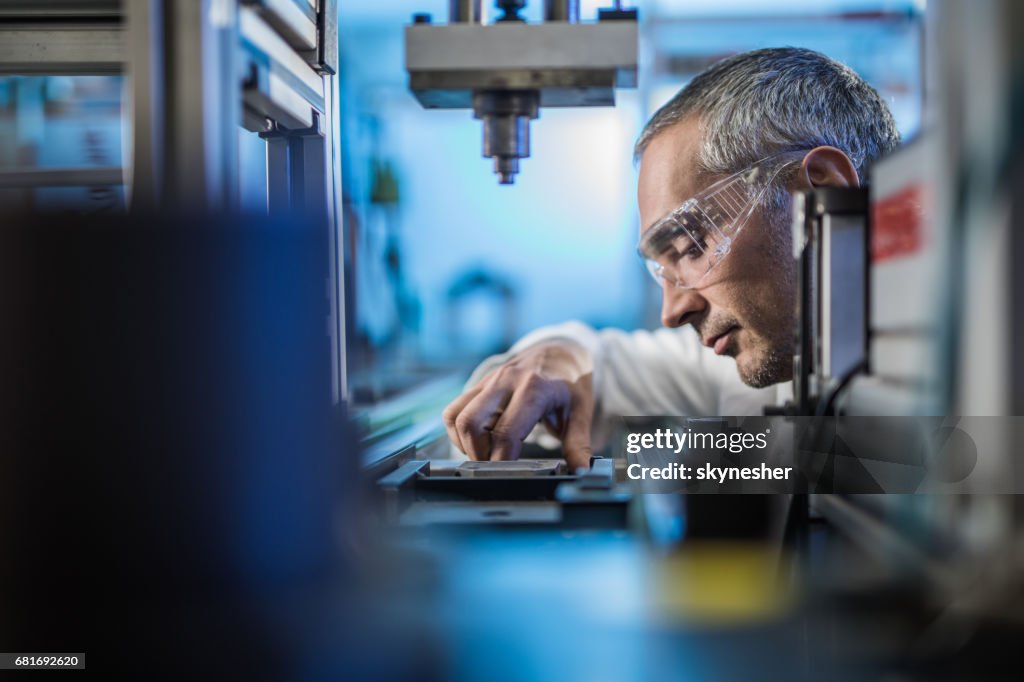 Contrôle de la qualité travailleur analysant des expériences scientifiques sur une machine de fabrication.