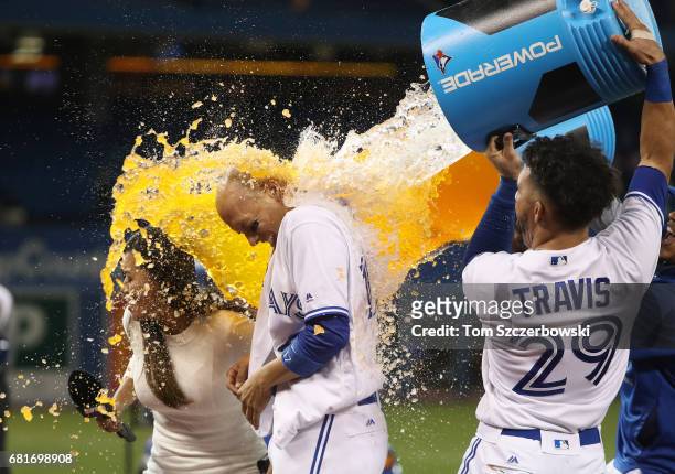 Ryan Goins of the Toronto Blue Jays is doused by Devon Travis after hitting a game-winning RBI single in the ninth inning during MLB game action...