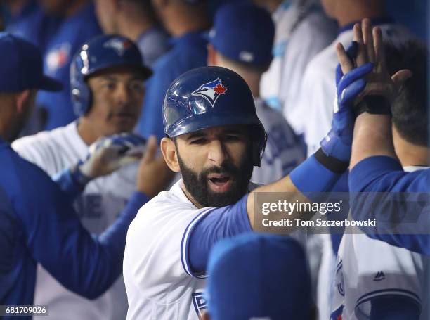 Jose Bautista of the Toronto Blue Jays is congratualted by teammates in the dugout after hitting a three-run home run in the first inning during MLB...