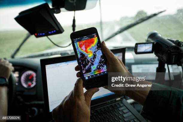 Support scientist Tim Marshall, a 40 year veteran of storm chasing, looks at radar on his smartphone as the group tracks a supercell thunderstorm,...