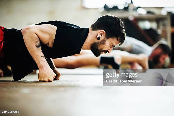 muay thai boxing athlete doing pushups - sports training stock-fotos und bilder