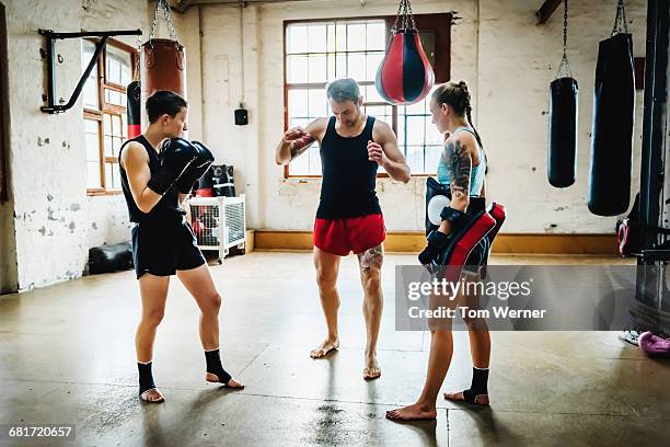 two female muay thai boxers with trainer in gym - kickboxing equipment stock pictures, royalty-free photos & images