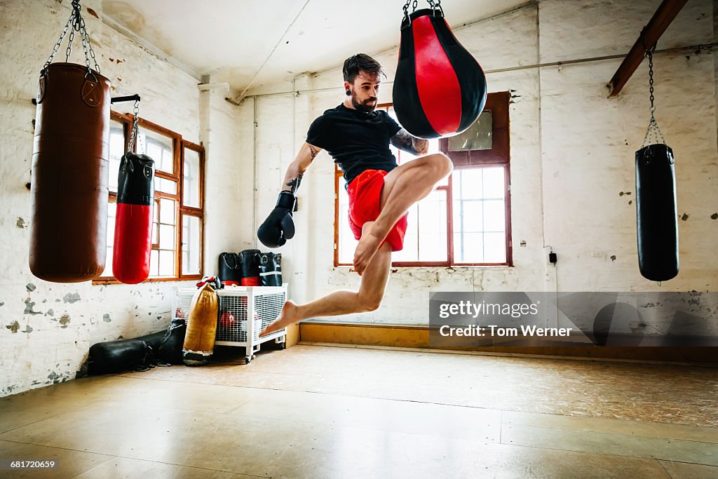 Muay thai boxer practicing kicks in gym