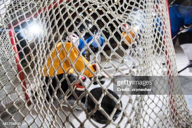 close up of ice hockey goalkeeper's net with hockey puck in it. - hockey puck in net stock pictures, royalty-free photos & images