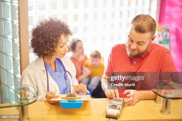 settling his family's medical bill - busy hospital lobby stock pictures, royalty-free photos & images