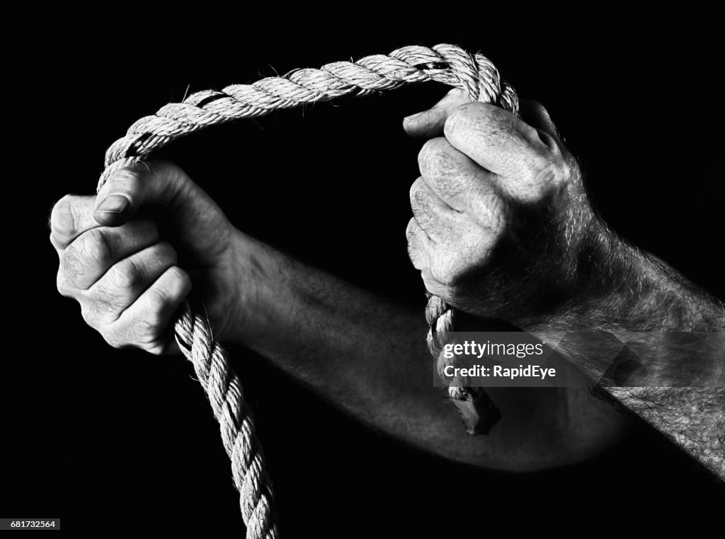 Masculine hands grip rope, pulling apart. Black and white.