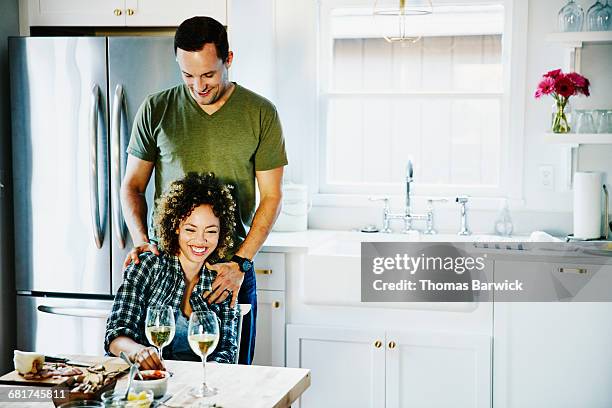 laughing husband and wife embracing in kitchen - andersherum stock-fotos und bilder