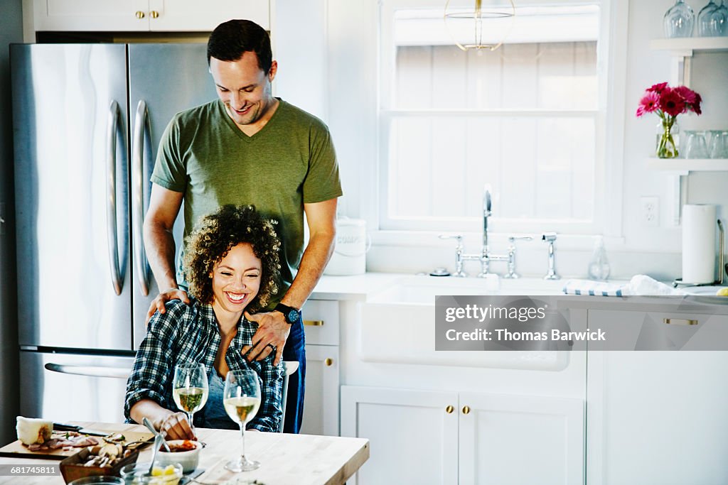 Laughing husband and wife embracing in kitchen