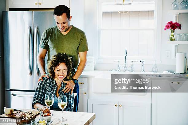 laughing husband and wife embracing in kitchen - back to front stock pictures, royalty-free photos & images