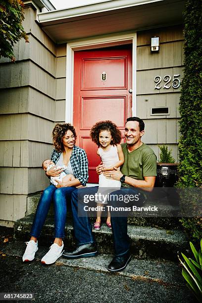 smiling family sitting together on front porch - family porch foto e immagini stock