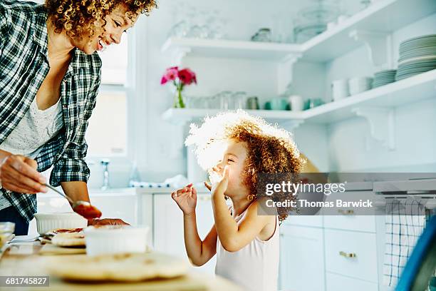 smiling young girl making pizza with mother - making pizza stock pictures, royalty-free photos & images