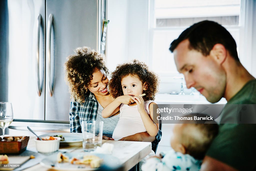 Mother holding daughter while family dines