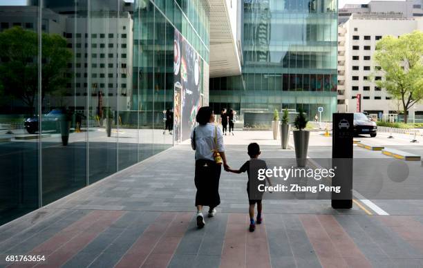 Young mother takes her only kid walking on the street. Since October of 2015, China's full implementation of the two child policy, the government had...