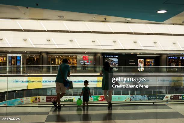 Couple of young parent with their only kid watch a indoor skating playground in a shopping mall. Since October of 2015, China's full implementation...