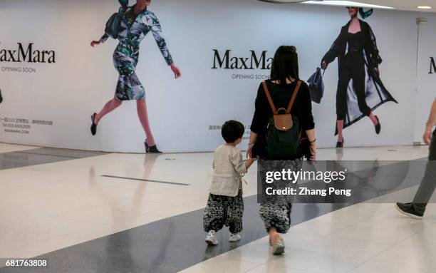 Young mother takes her only kid walking in a shopping mall. Since October of 2015, China's full implementation of the two child policy, the...