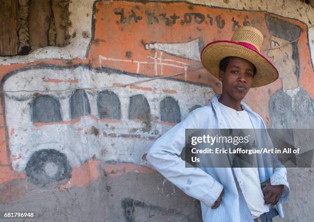 Ethiopian young man with a hat standing in front of his traditional painted house, Kembata, Alaba Kuito, Ethiopia on March 9, 2016 in Alaba Kuito,...