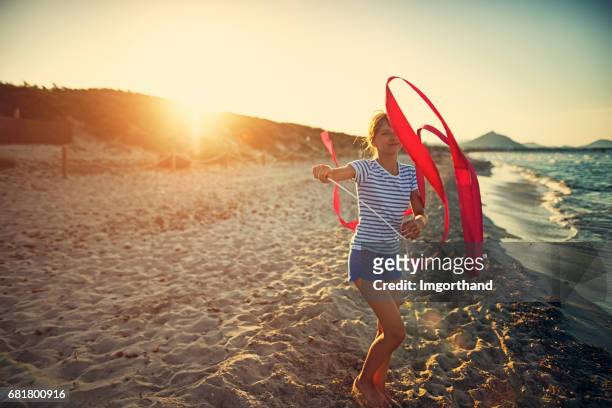 kleines mädchen mit gymnastik band am strand spielen. - ribbon dance stock-fotos und bilder