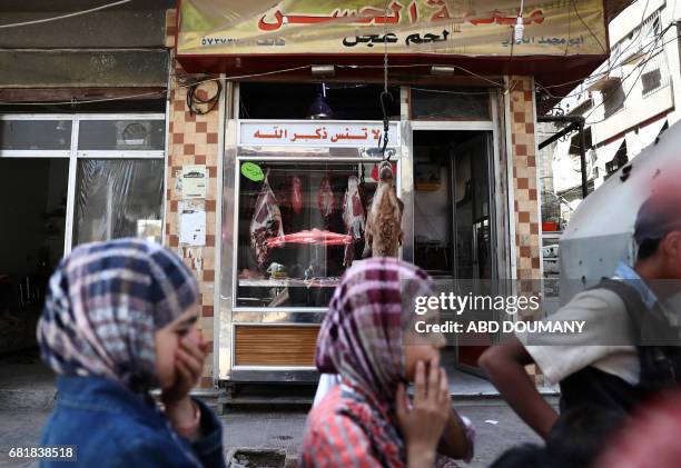 Syrian children watch as a butcher slaughters a camel in the rebel-held town of Douma, on the eastern outskirts of Damascus on May 11, 2017. Before...