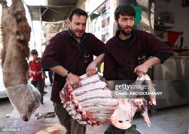 Syrian children watch as a butcher slaughters a camel in the rebel-held town of Douma, on the eastern outskirts of Damascus on May 11, 2017. Before...