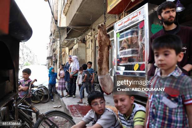 Syrian children watch as a butcher slaughters a camel in the rebel-held town of Douma, on the eastern outskirts of Damascus on May 11, 2017. Before...