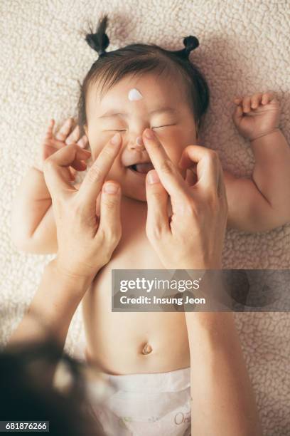 baby girl (6-11 months) receiving hand massage - korean baby girl stock-fotos und bilder