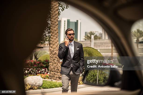 car window view of businessman talking on smartphone outside hotel, dubai, united arab emirates - city walk dubai stockfoto's en -beelden