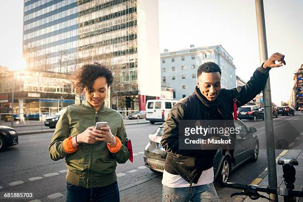 teenagers using phone while standing on sidewalk by city street - stockholm city stock pictures, royalty-free photos & images