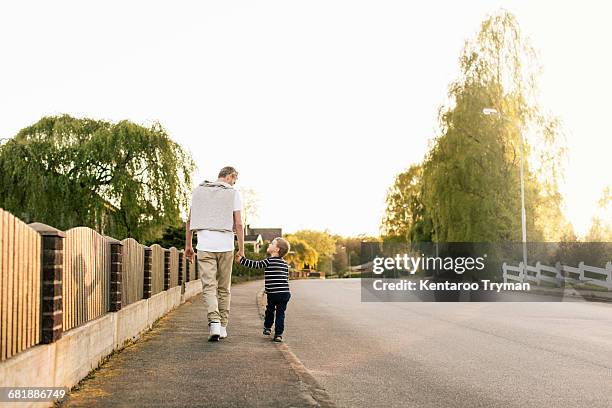 father and son talking while walking on roadside against clear sky - roadside photos et images de collection