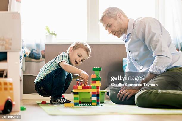 father and son playing with toy blocks while sitting at home - playing toy men stock pictures, royalty-free photos & images
