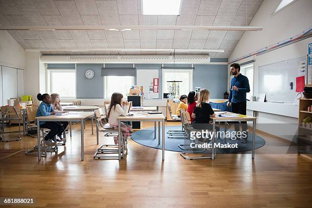 teacher teaching students in brightly lit classroom at school - 5-10 2016 stock pictures, royalty-free photos & images