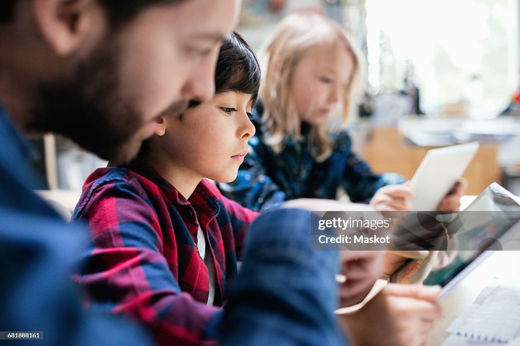 Close-up of teacher explaining students to use digital tablet at desk