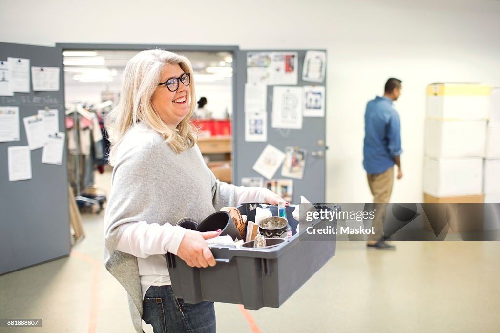 Smiling volunteer carrying crate while walking at workshop