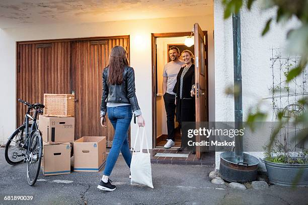 parents looking at daughter walking by cardboard boxes and bicycle outside house - apartment front door foto e immagini stock