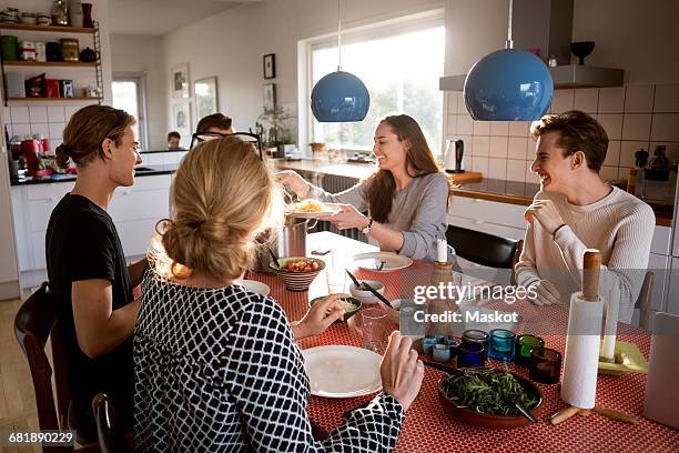 woman serving food for family at dining table - familie warm stock pictures, royalty-free photos & images