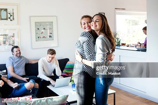 happy mother and daughter embracing while family sitting on sofa in living room - son daughter stock pictures, royalty-free photos & images