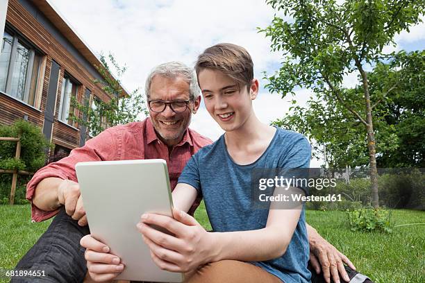 happy father and son sharing digital tablet in garden - boy computer smile fotografías e imágenes de stock