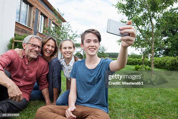 teenage boy taking a selfie of happy family sitting in garden - family formal portrait stock pictures, royalty-free photos & images