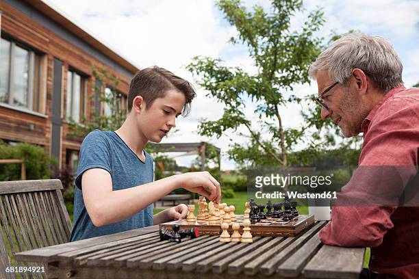 father and son playing chess in garden - kids playing chess stock pictures, royalty-free photos & images