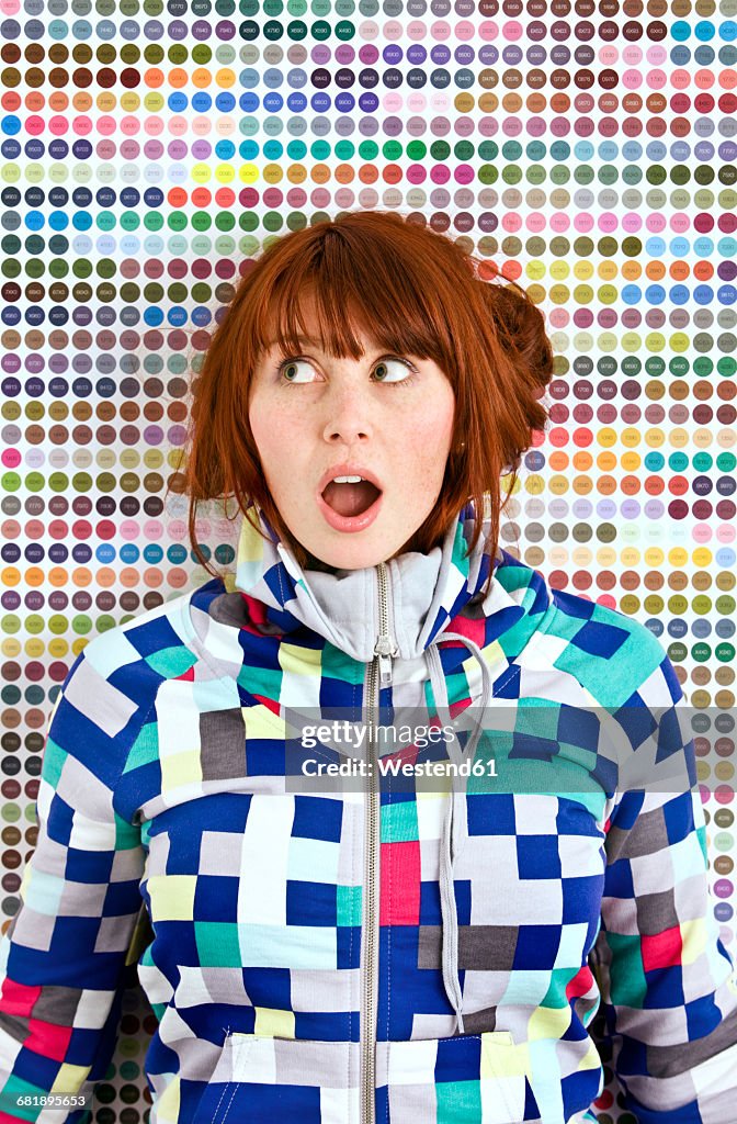 Young woman wearing patterned jacket in front of dotted wall