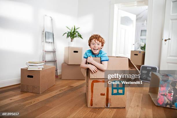 happy boy looking out of a cardboard box in new apartment - redhead boy fotografías e imágenes de stock